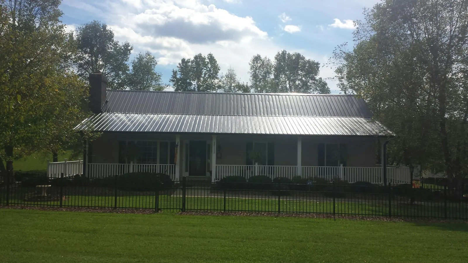 Gray metal roof on a brick ranch with a full width front porch — Gutter Guard Installation work by our crew in Atlanta